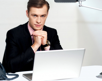 mladý muž v obleku sedí za notebookem